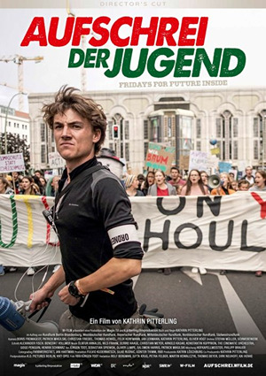 Mann in schwarzem Shirt bei einer Demonstration mit Banner im Hintergrund.