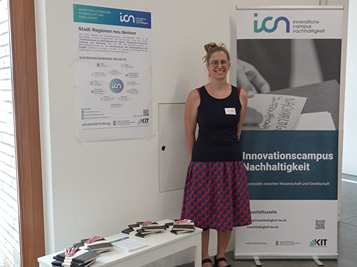 Frau vor einem Informationsbanner und Poster zum Innovationscampus Nachhaltigkeit.